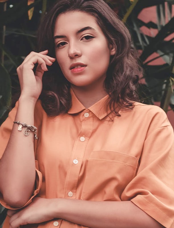 An image of a girl in a salmon-coloured shirt looking towards the viewer.